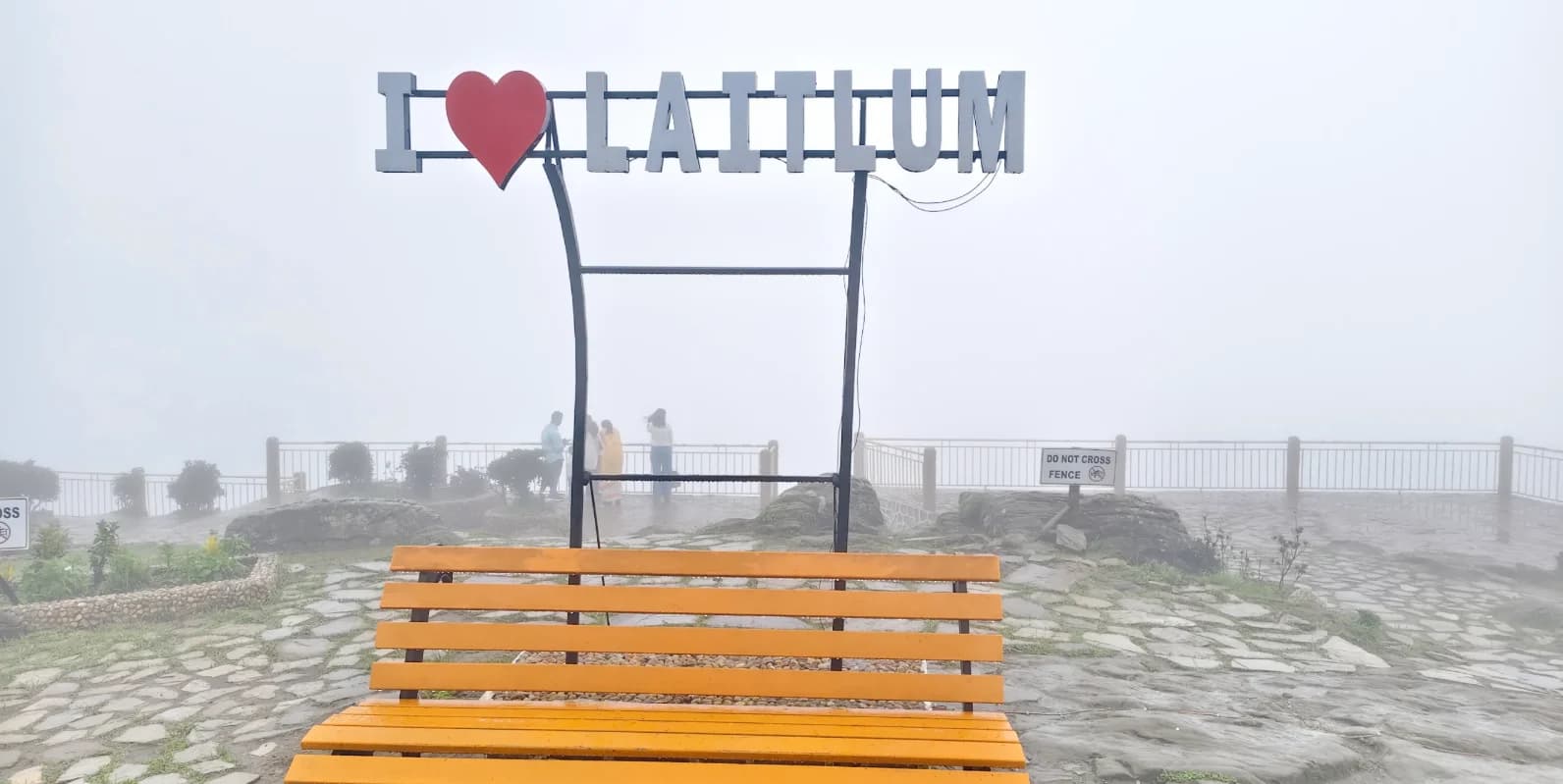 An orange bench beneath the I love Laitlum sign in thick mist