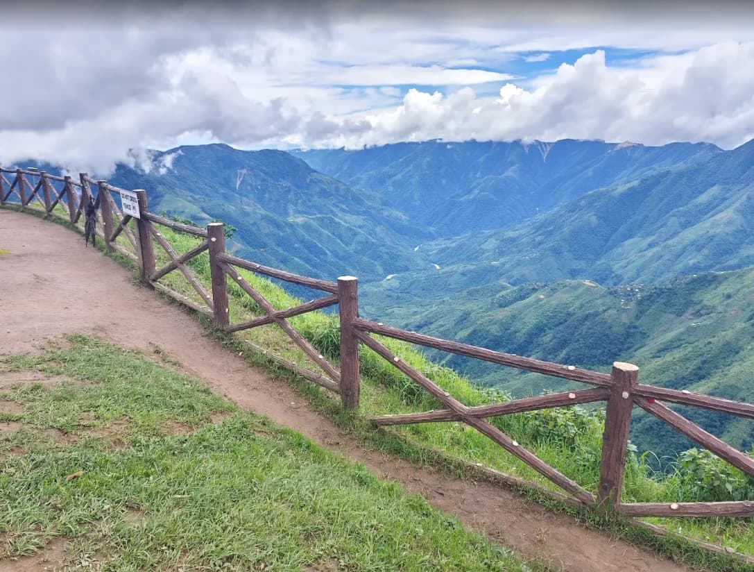 A viewpoint footpath beside a wooden railing overlooking the green canyon